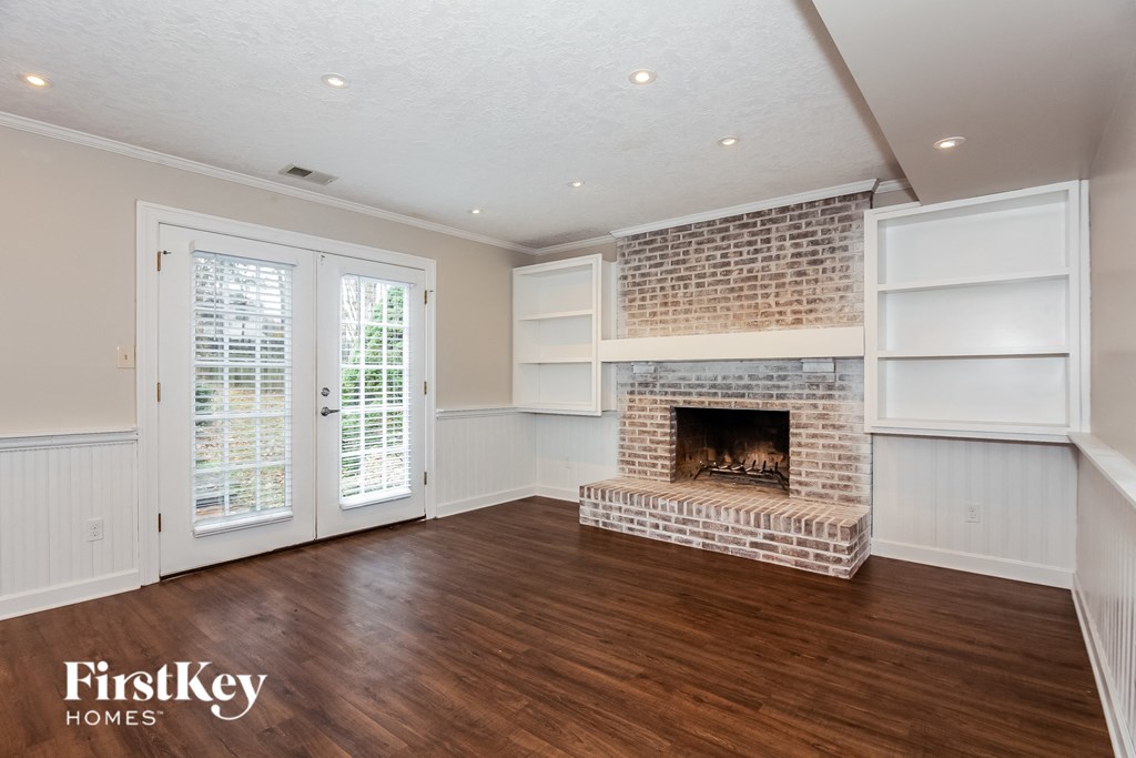 a living room with a brick fireplace and wooden floors