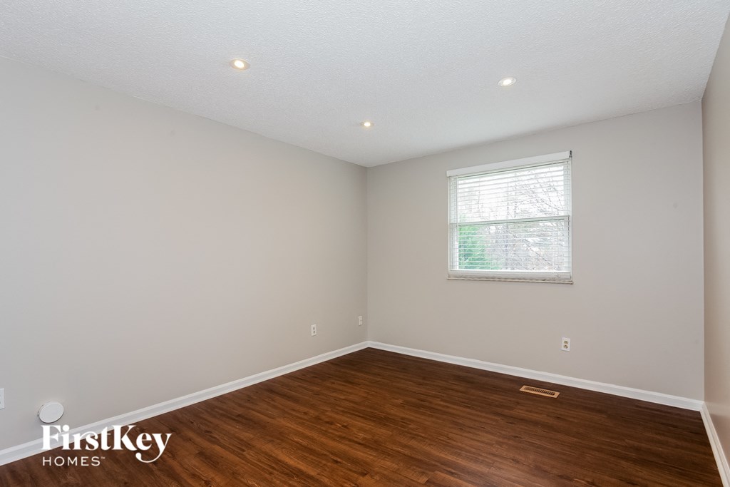 the living room of a home with wood flooring and a window