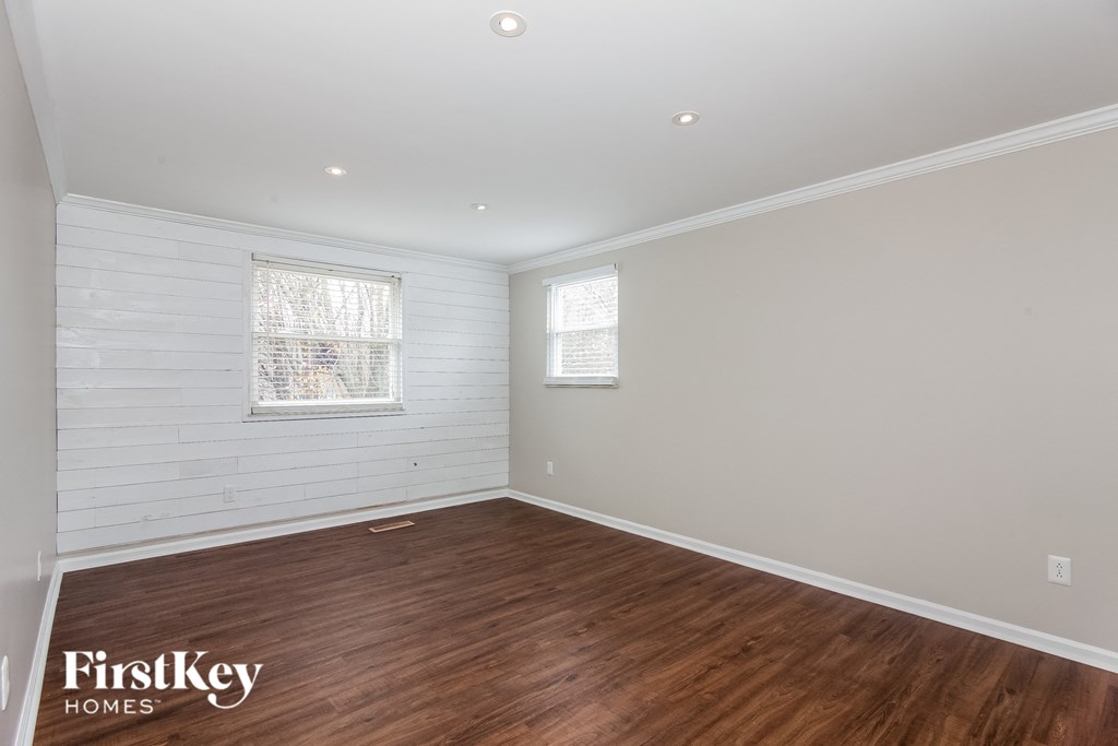 a living room with wood floors and white walls and a window