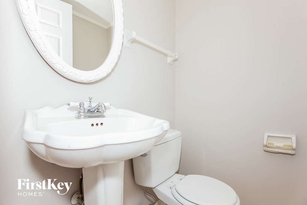 a white bathroom with a white sink and toilet and a white mirror