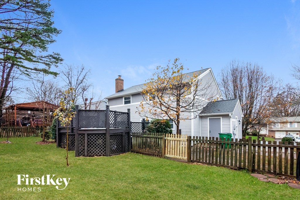 a backyard with a fence and a white house with a deck