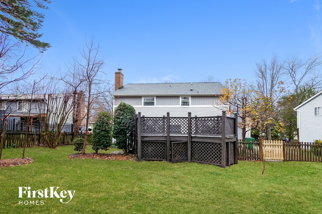 a backyard deck with a privacy fence and a white house