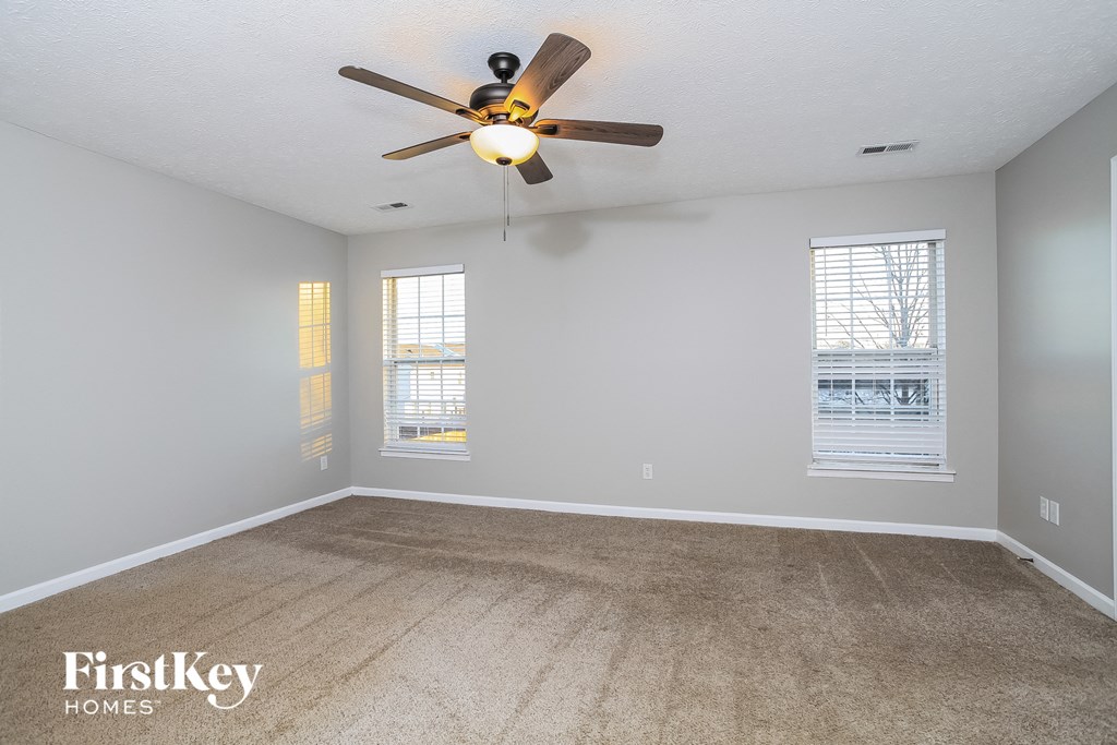the living room of an empty house with a ceiling fan