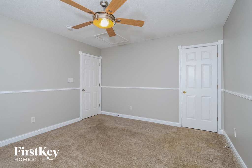 the master bedroom has a ceiling fan and a carpet