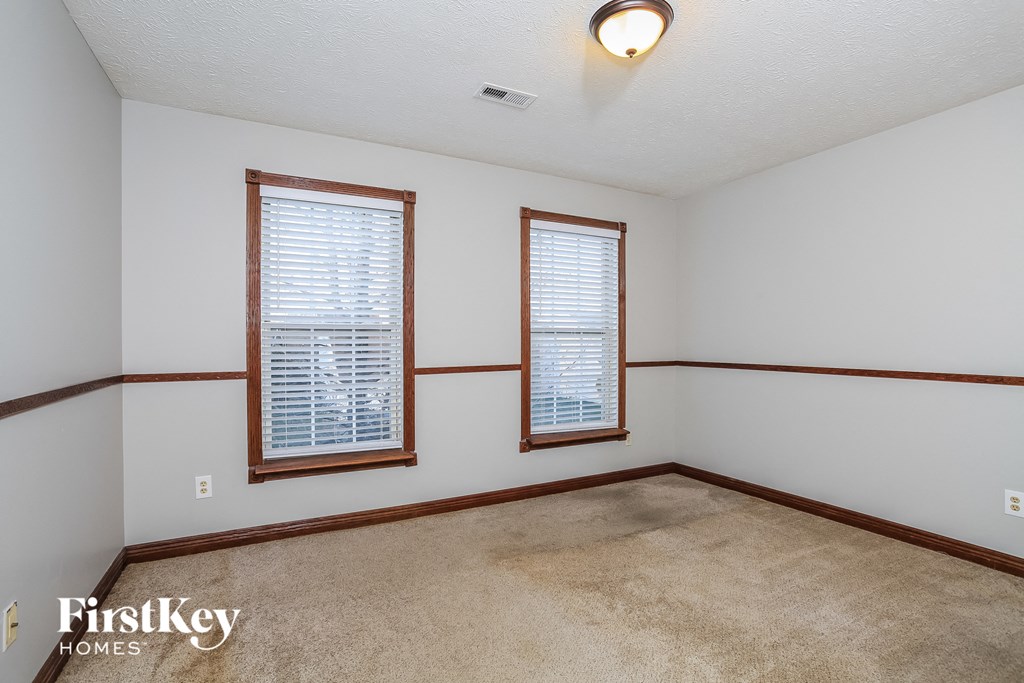 a living room with two windows and a carpet