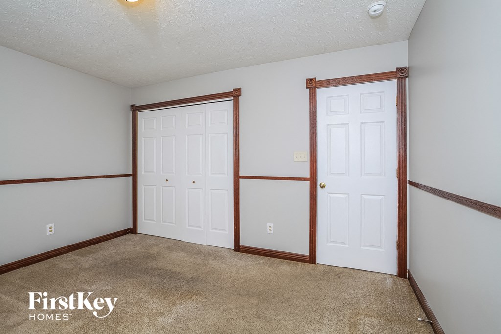 a bedroom with two closets and a carpeted floor and two doors