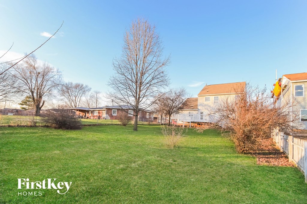 a yard with a fence and houses in the background
