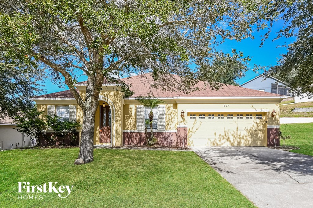 a house with a garage and a tree in front of it