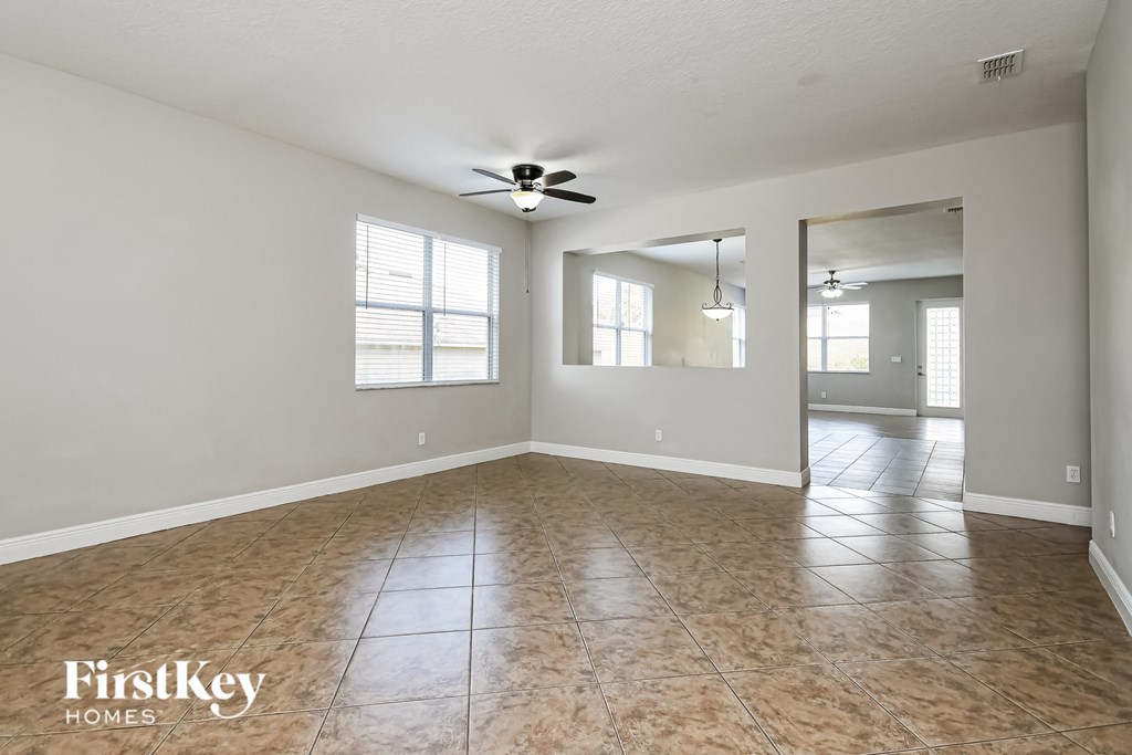 an empty living room with a ceiling fan and a window