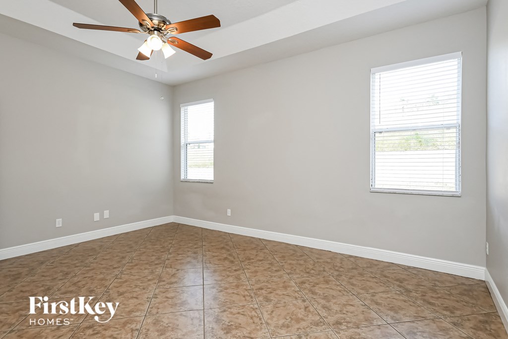 an empty room with a ceiling fan and two windows