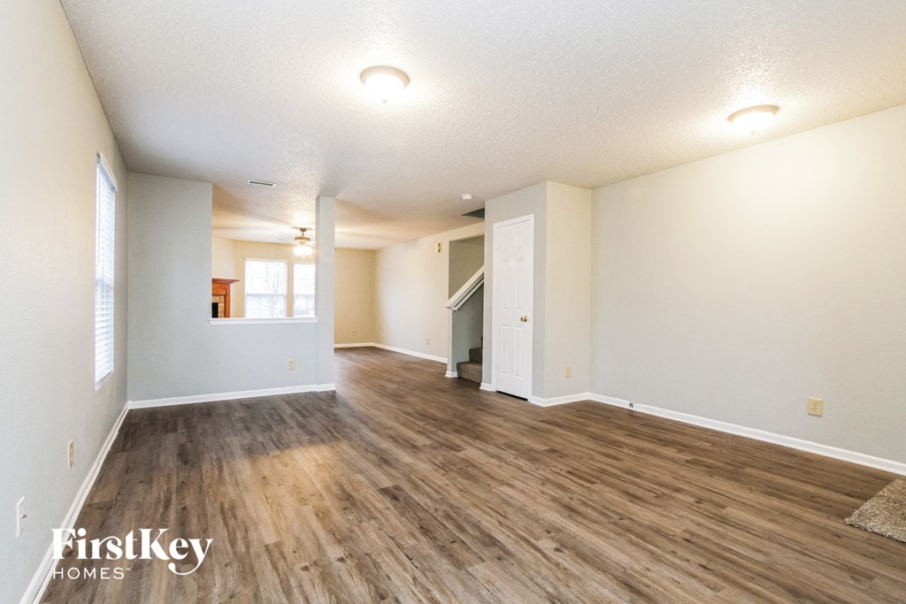 the living room and dining room with hardwood floors and white walls