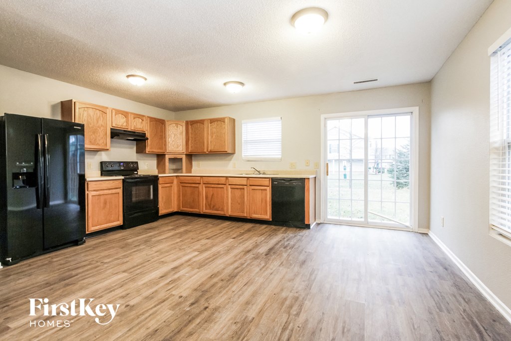 a kitchen with black appliances and wooden cabinets and a door