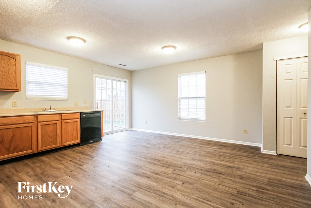 the kitchen and living room of an empty house with wood flooring