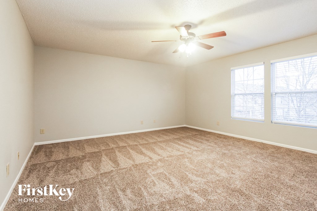 the spacious living room with carpeting and a ceiling fan