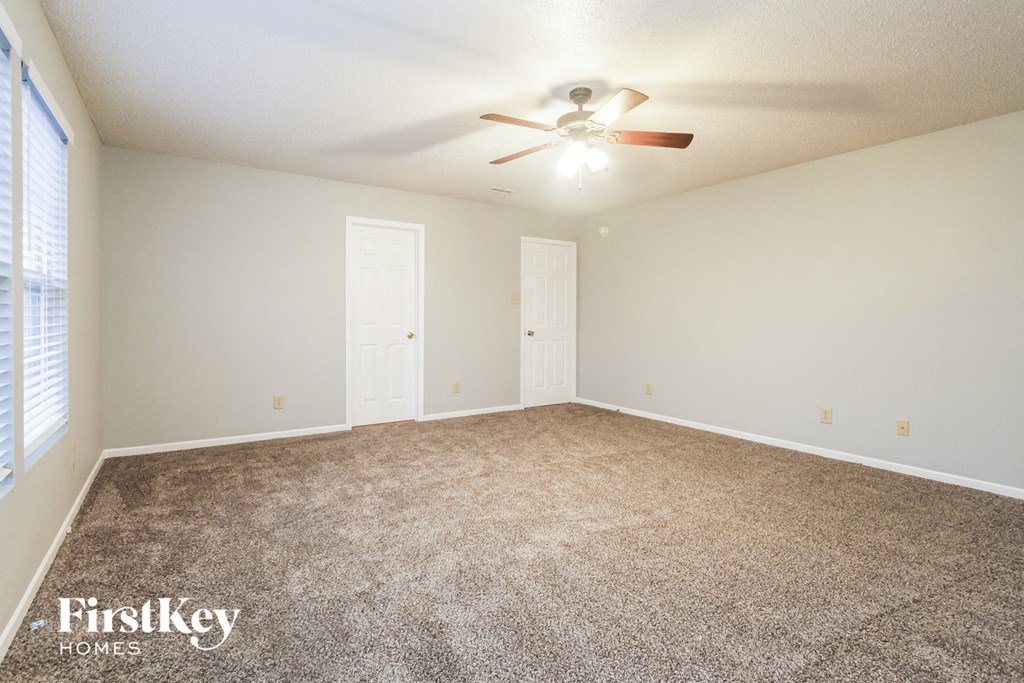 the spacious living room with carpeting and a ceiling fan