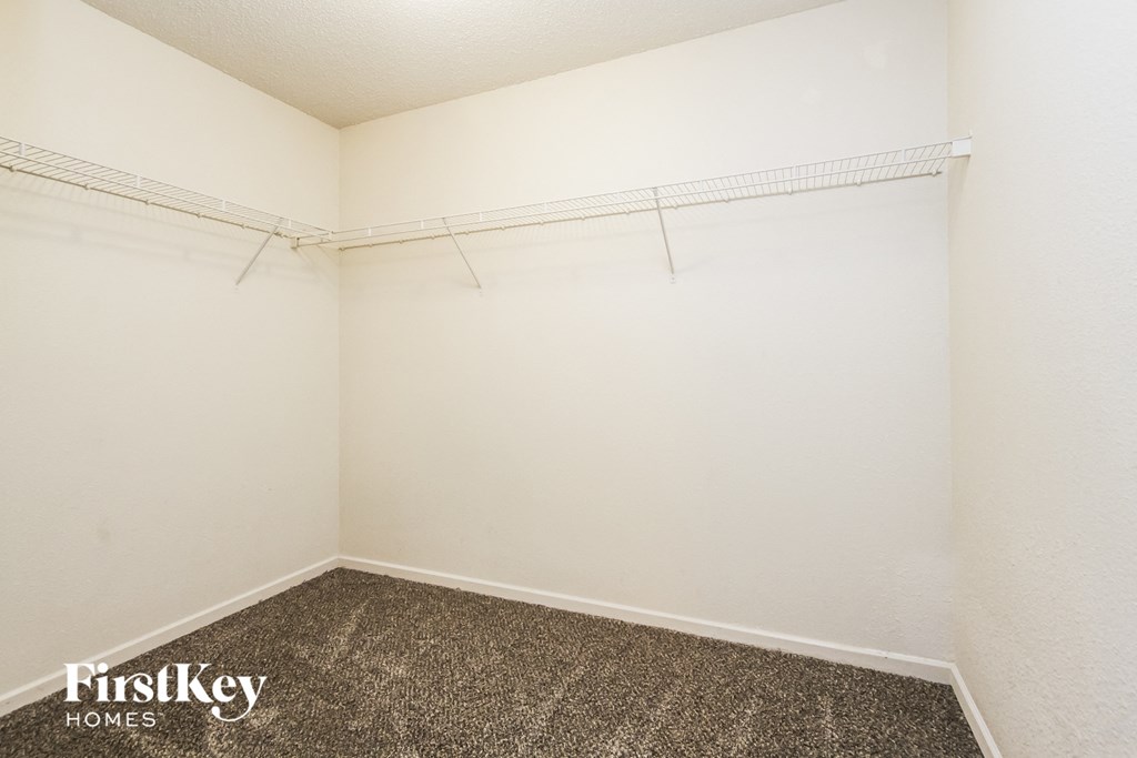 a empty room with a carpeted floor and a white wall with a hanging rack