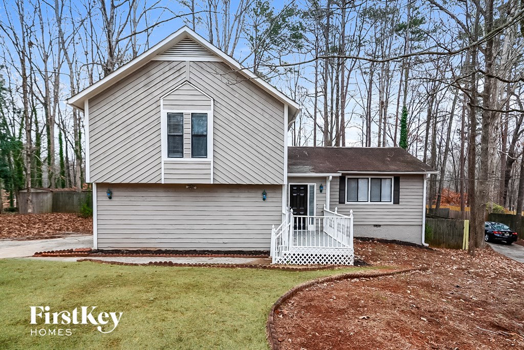 A house with a porch and a tree in the background.