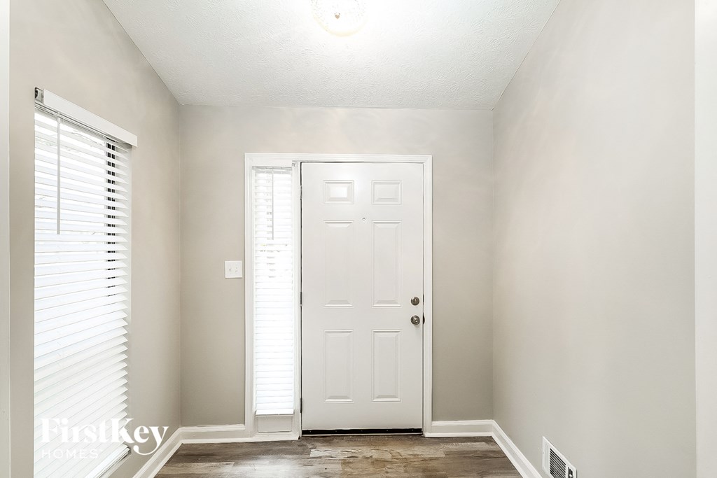 A white door is in a room with a window on the left.