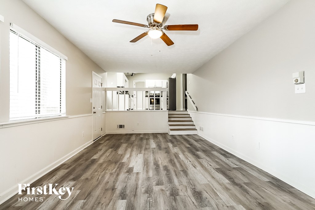 A spacious room with wooden floors and a ceiling fan.