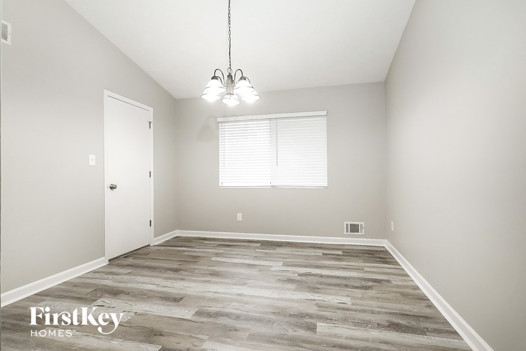 A room with wooden flooring and a chandelier hanging from the ceiling.