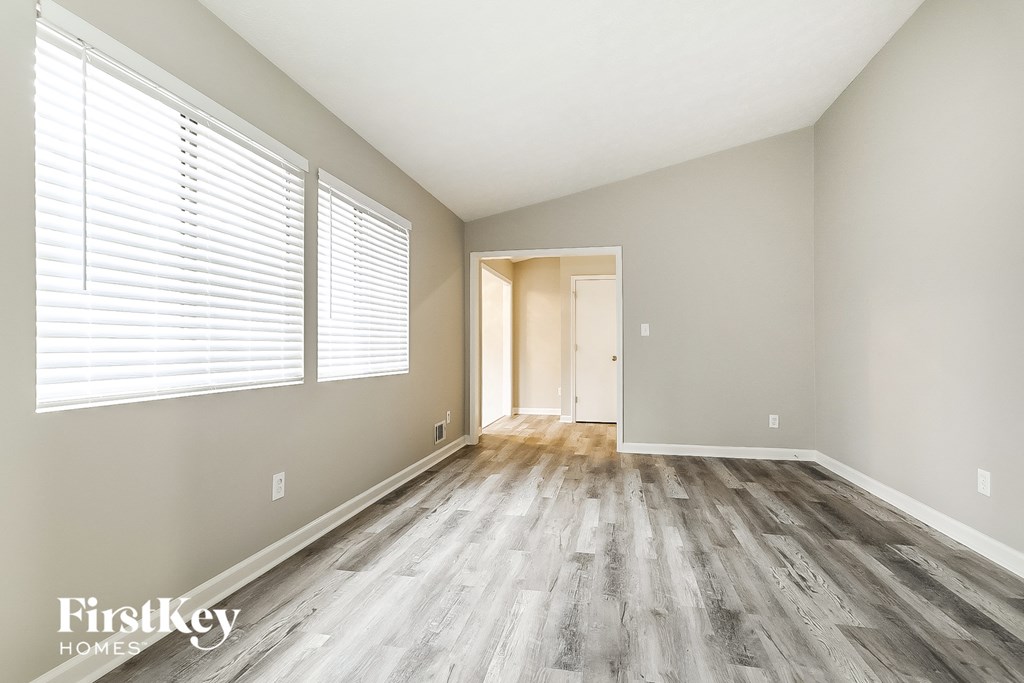 A room with wooden flooring and a doorway leading to another room.