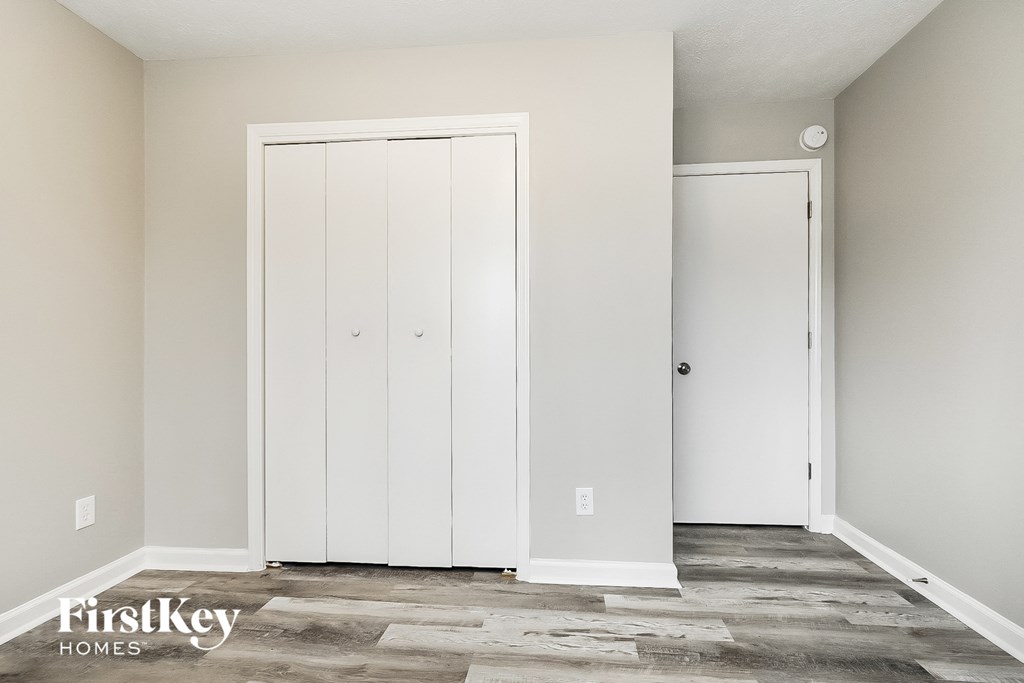 A room with a white door and a carpeted floor.