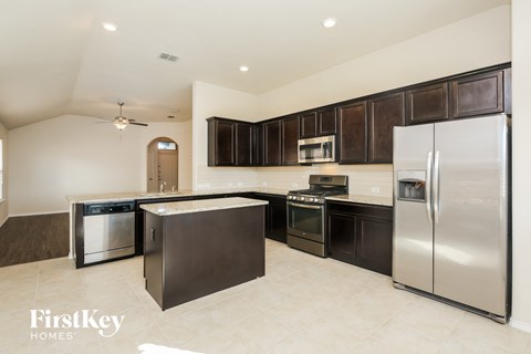 A kitchen with a refrigerator, oven, and microwave.