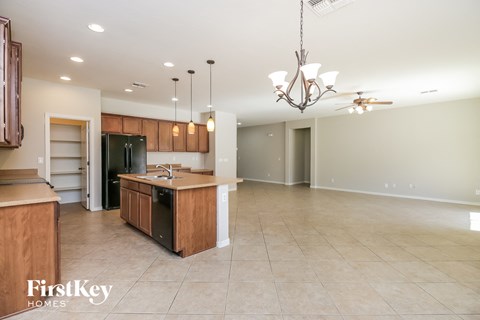 an open kitchen and living room with an island and a black refrigerator