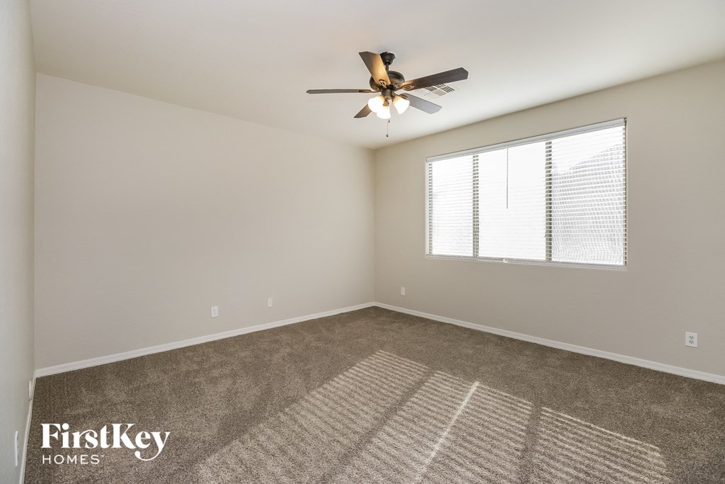 the spacious living room with ceiling fan and window