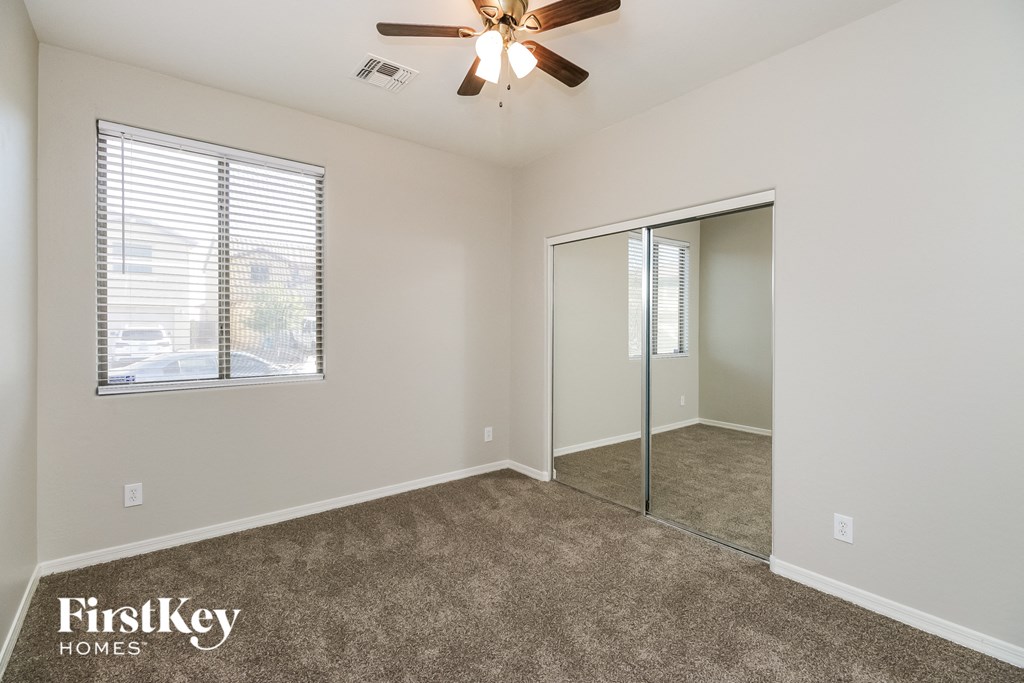 a bedroom with a ceiling fan and a mirrored closet