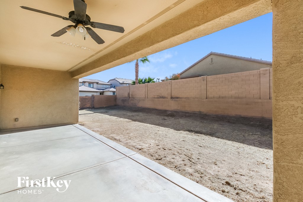 a patio with a ceiling fan and a yard with dirt