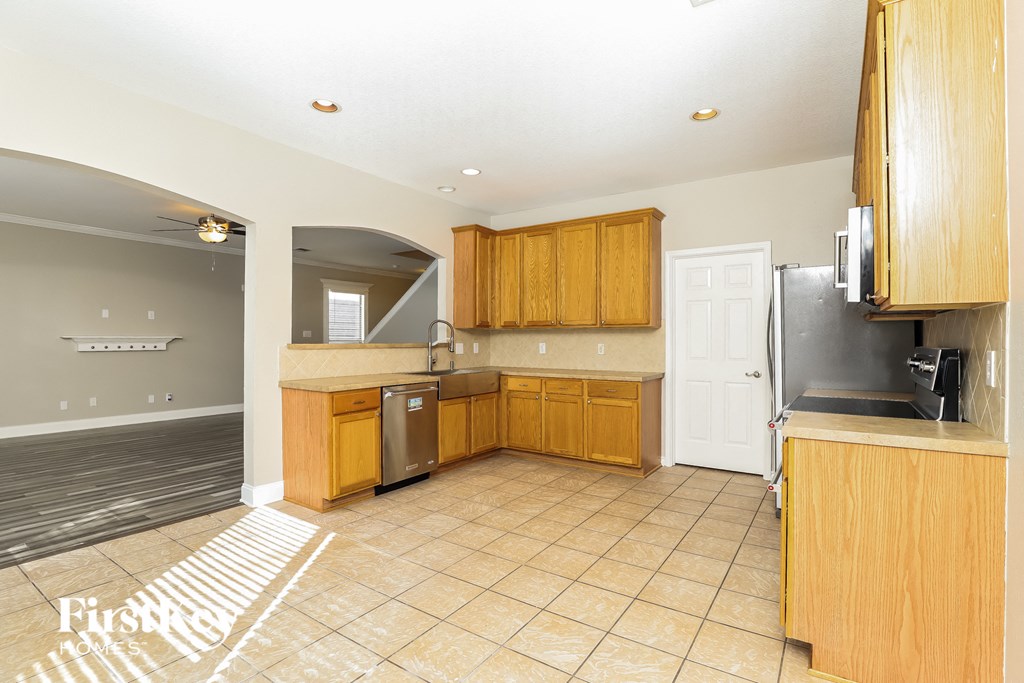 an empty kitchen with wooden cabinets and a stainless steel refrigerator