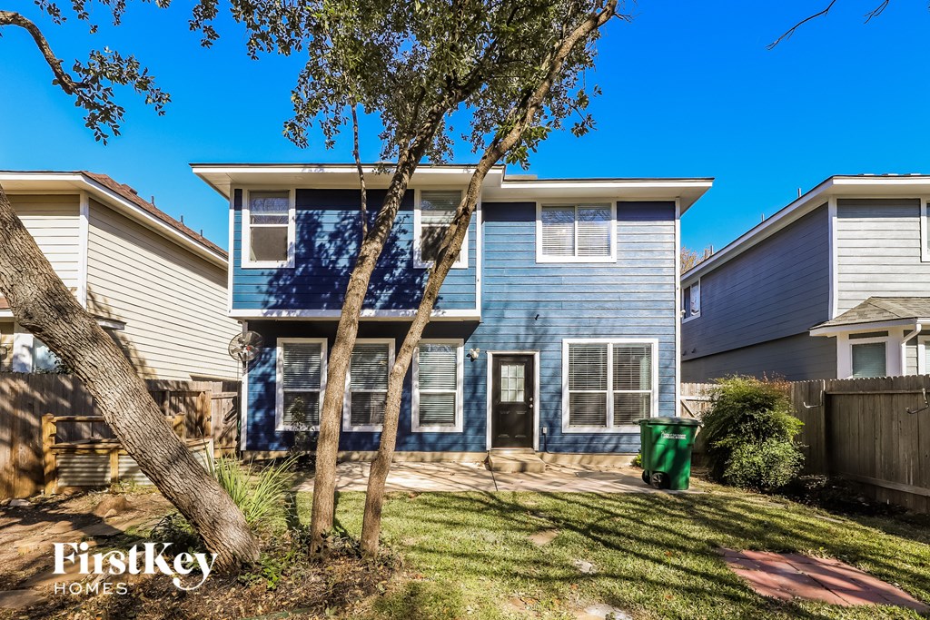 a blue and white house with a yard and trees