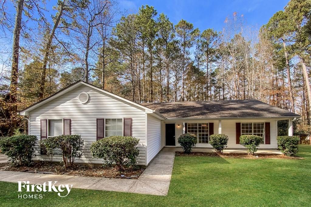 a small white house with a lawn and trees