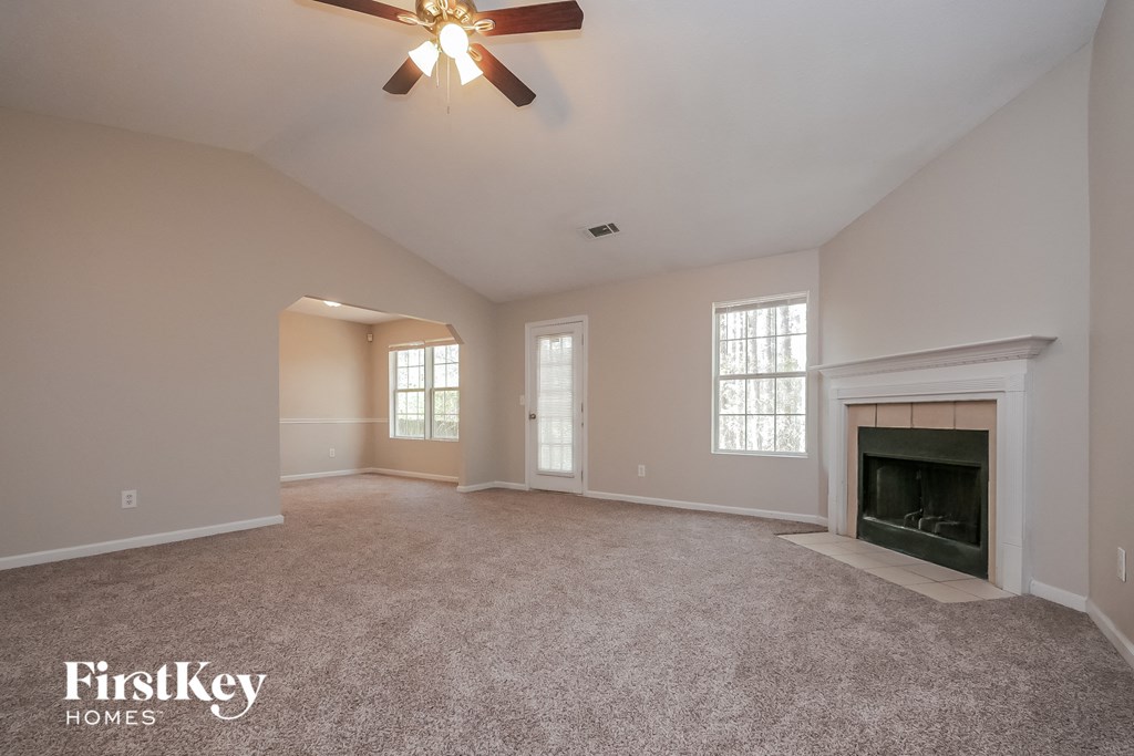 the spacious living room with fireplace and ceiling fan