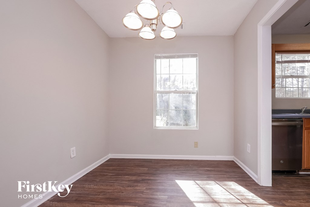 a living room with white walls and wooden floors and a window