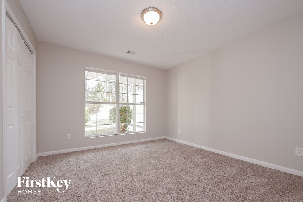 a bedroom with carpet and a large window