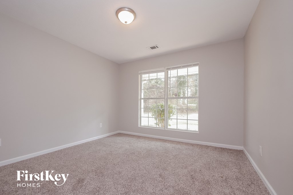 the master bedroom has a carpeted floor and a large window