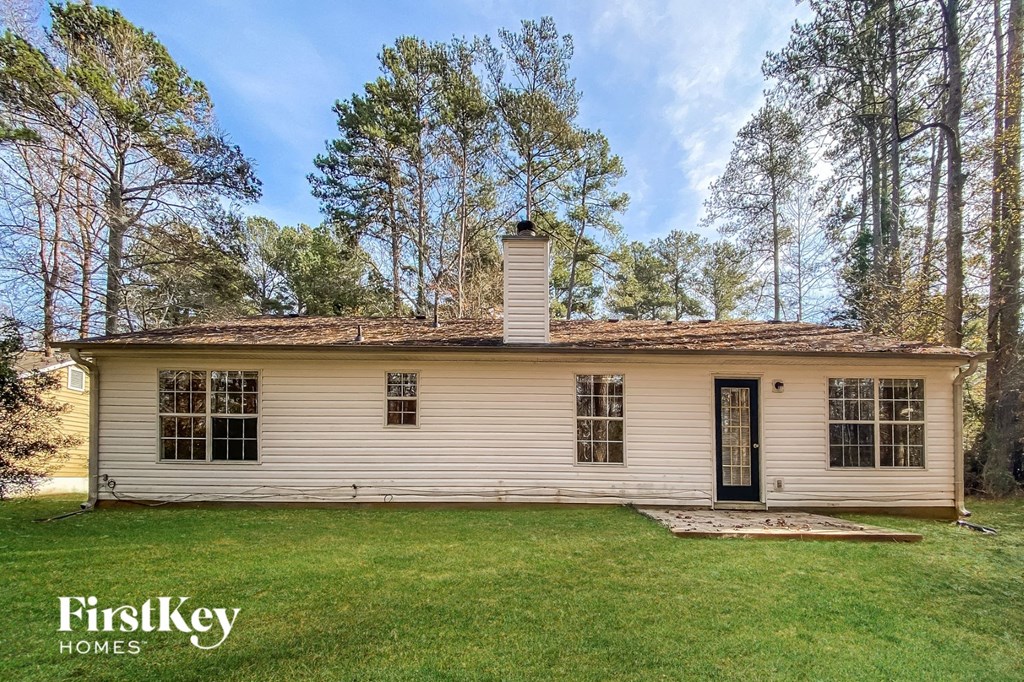 a small white house with a green lawn and trees