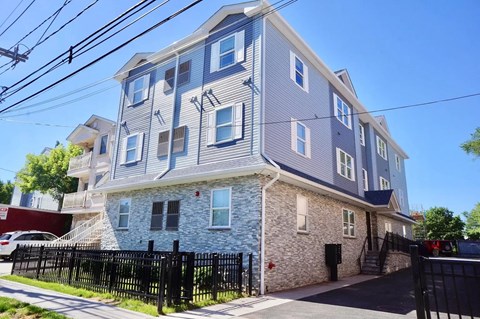 a grey and blue apartment building with a black fence