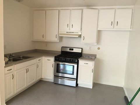 A kitchen with white cabinets and a black stove top oven.