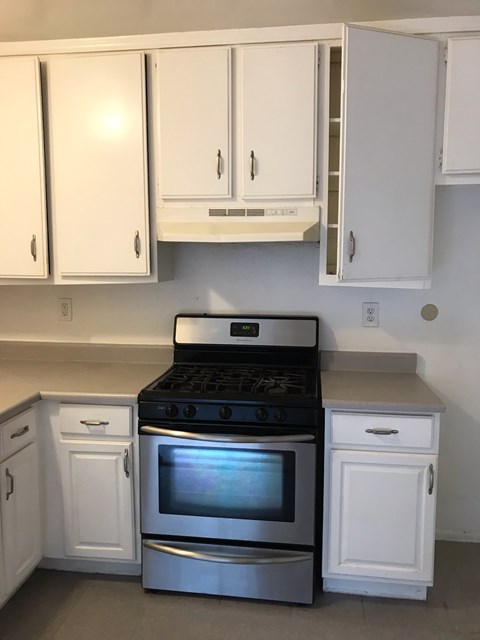 A white kitchen with a black stove top oven.
