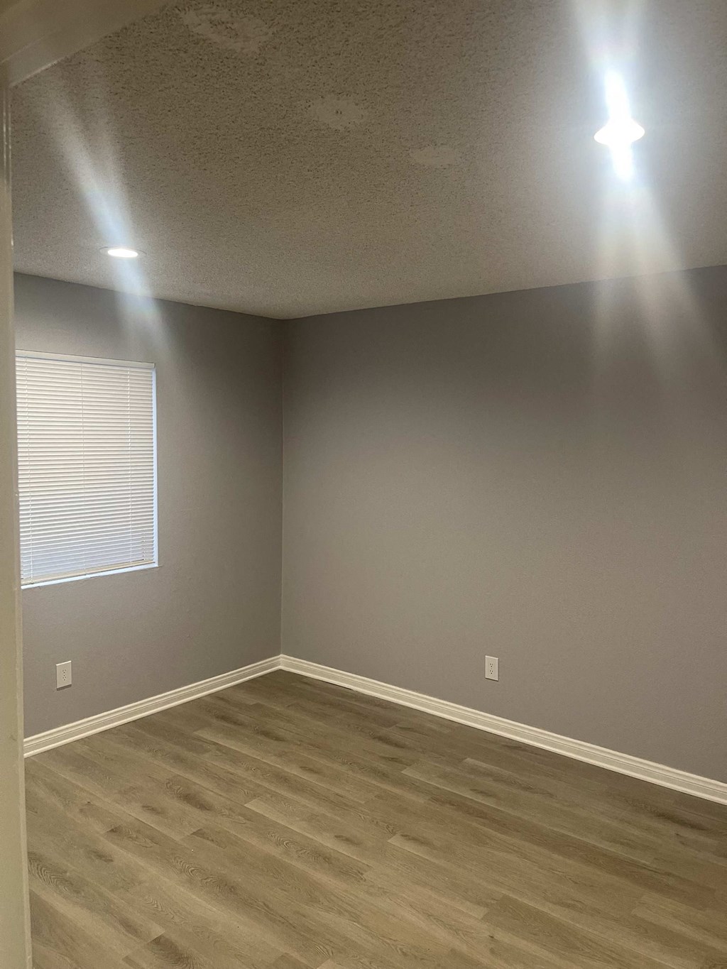 a room with grey walls and wooden floors and a window