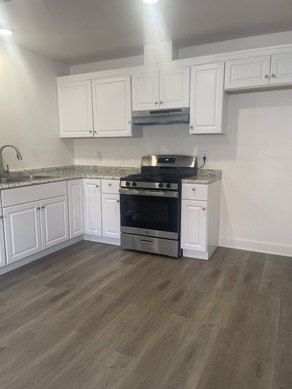 a kitchen with white cabinets and stainless steel appliances and a wooden floor