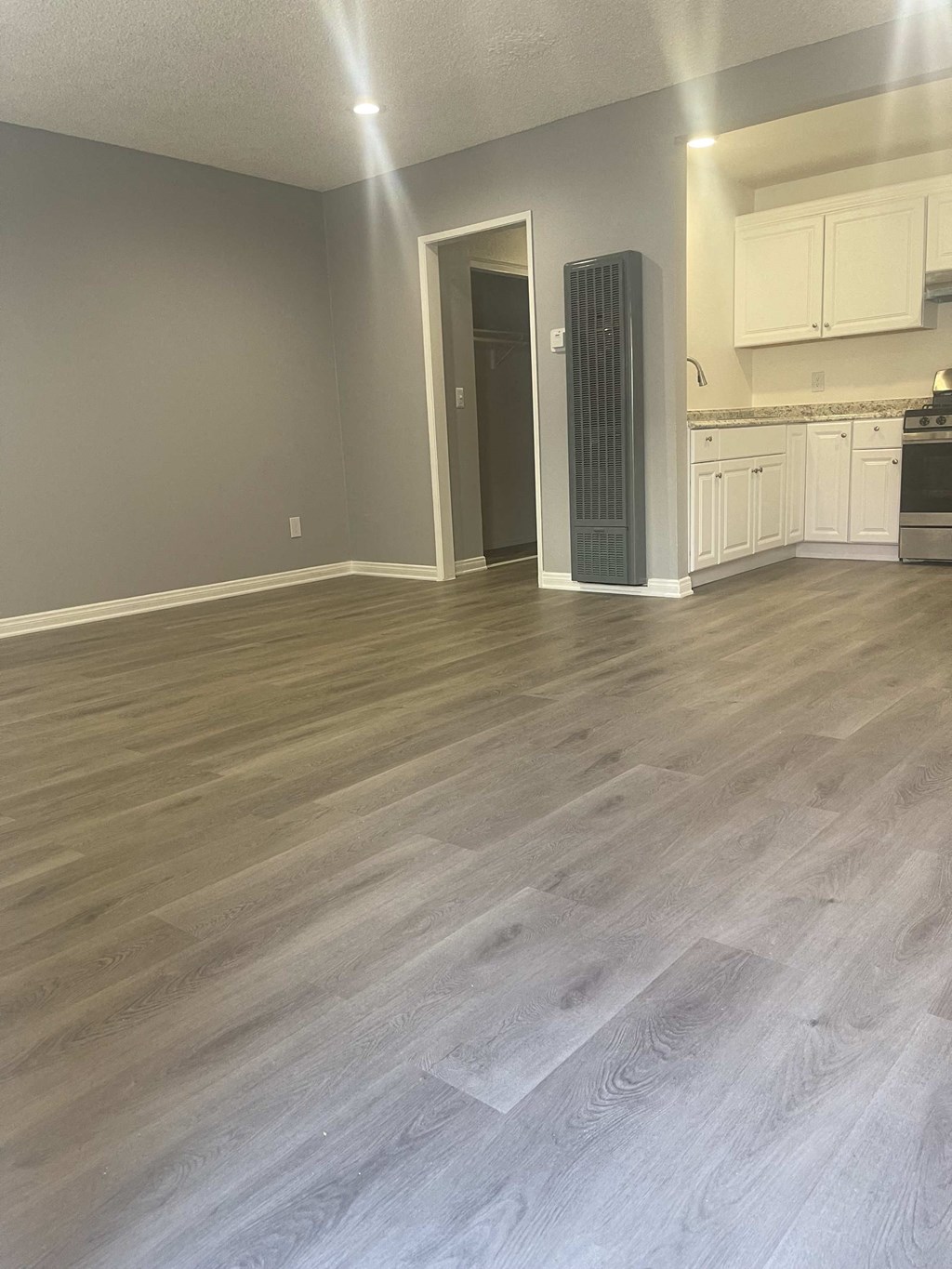 an empty living room with wooden floors and a kitchen