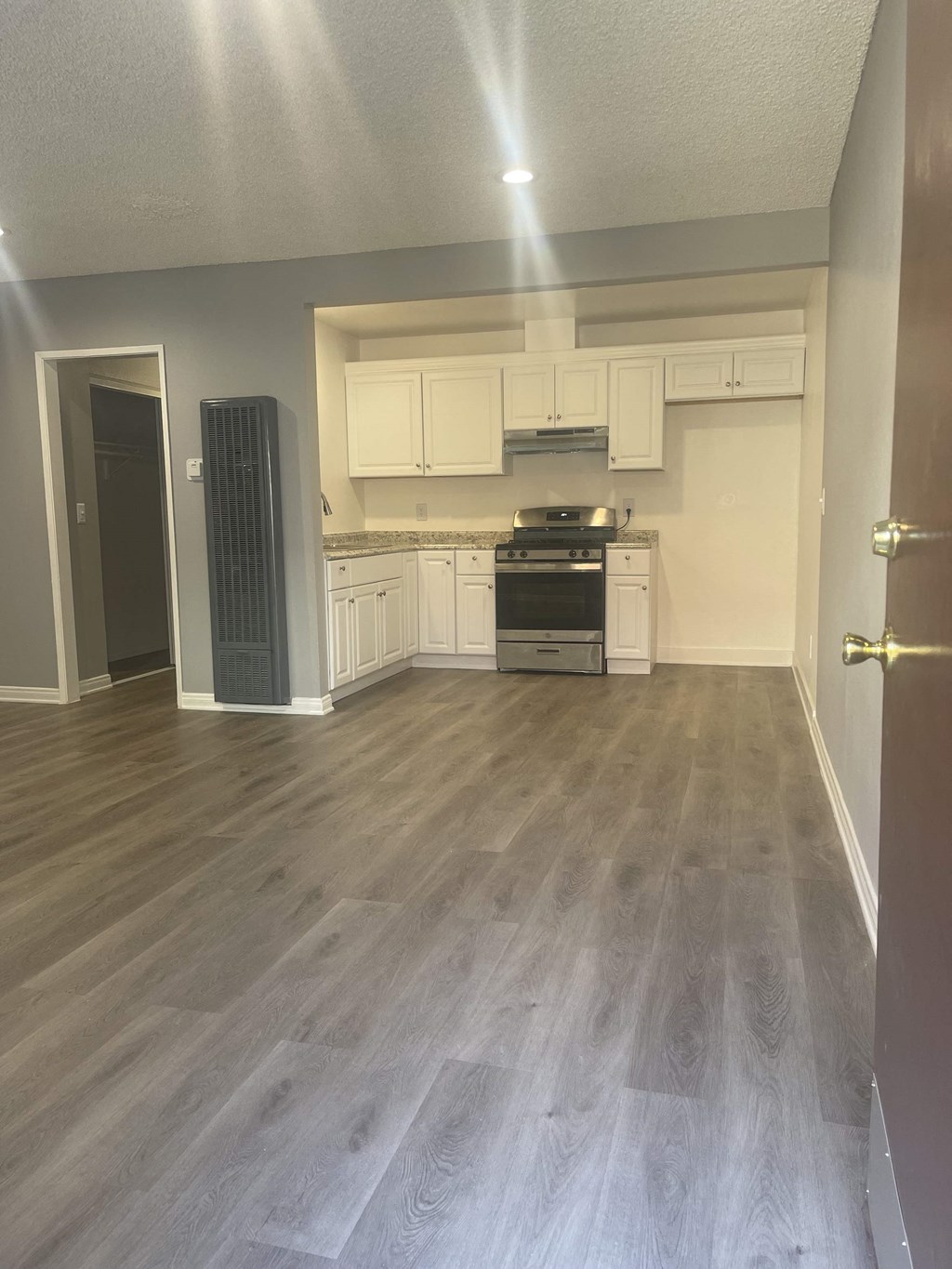 a renovated kitchen with white cabinets and a wood floor
