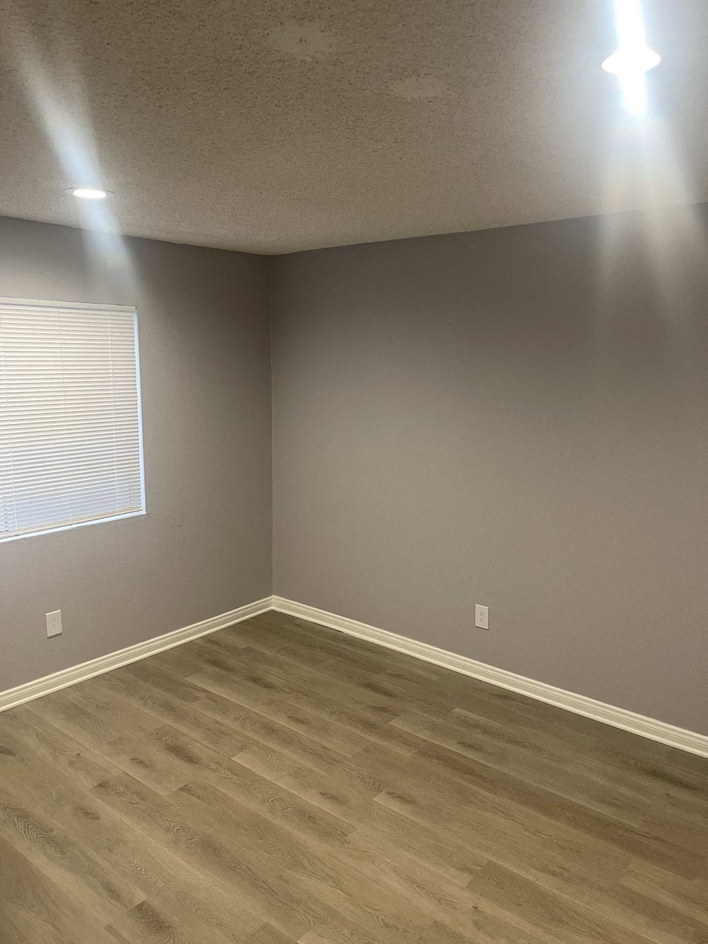 a room with wooden floors and gray walls and a window