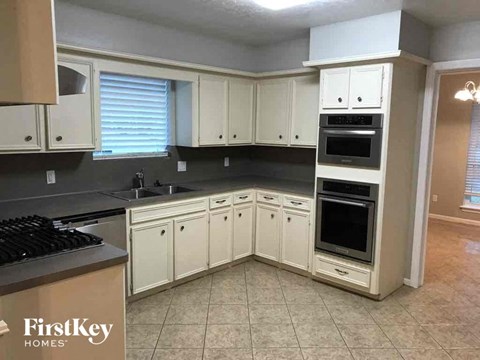A kitchen with white cabinets and a black stove top.