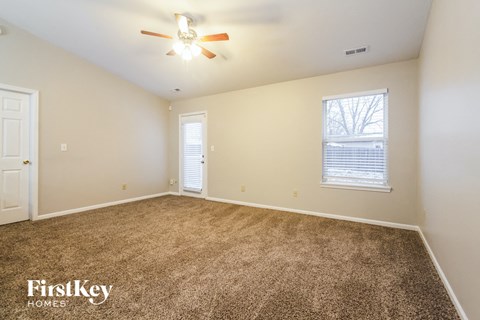 a spacious living room with carpet and a ceiling fan