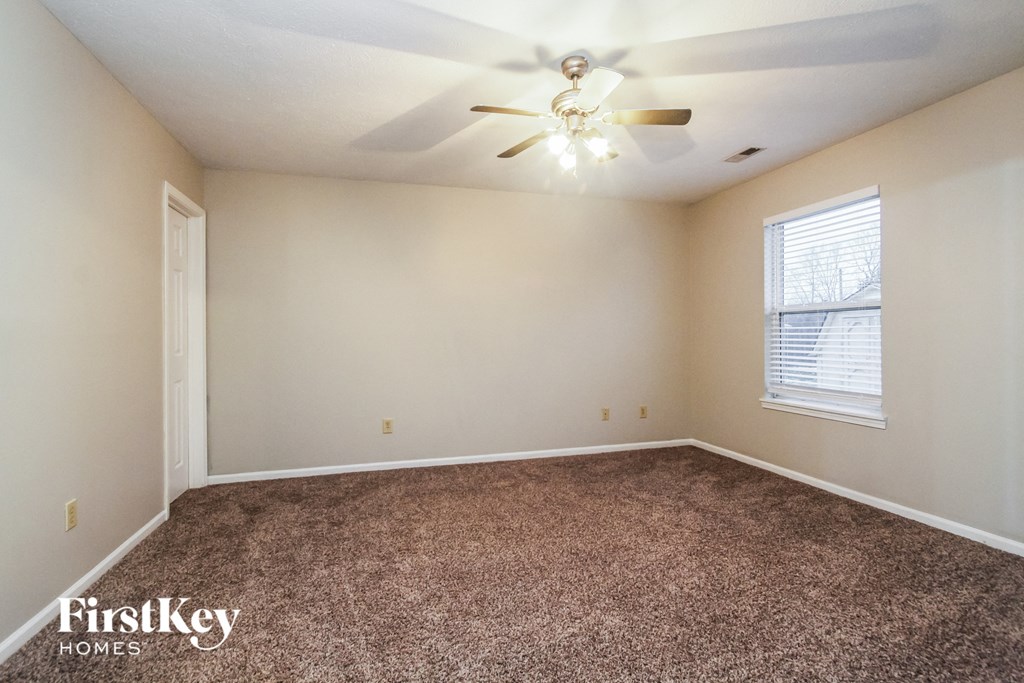 a bedroom with carpet and a ceiling fan and a window